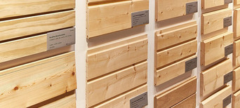 Ausstellung von verschiedenen gehobelten Holzprofilen mit Beschriftung, geeignet für Fassaden- und Innenverkleidung.