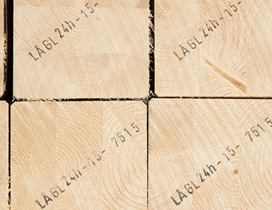 Gestapelte Brettschichtholzbalken mit sichtbarer Jahresringstruktur und Markierungen für den Holzbau.
