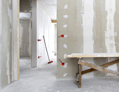 Rohbau mit verspachtelten Gipskartonwänden, Holzbock als Werkbank und sichtbaren Elektroinstallationen im Trockenbau.