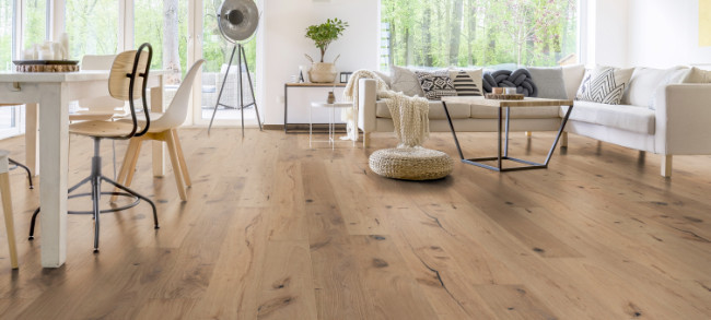 Im Wohnzimmer wurde Parkett in Langdielen-Optik verlegt. Ein Sofa und einige liebevoll platzierte Dekoelemente runden das gemütliche Ambiente ab.