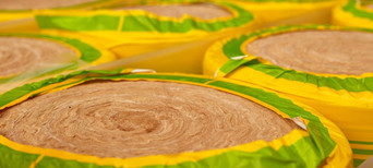 Gerollte Dämmwolle in gelb-grüner Verpackung, bereit für den Einsatz in Wärmedämmung und Schallschutz.